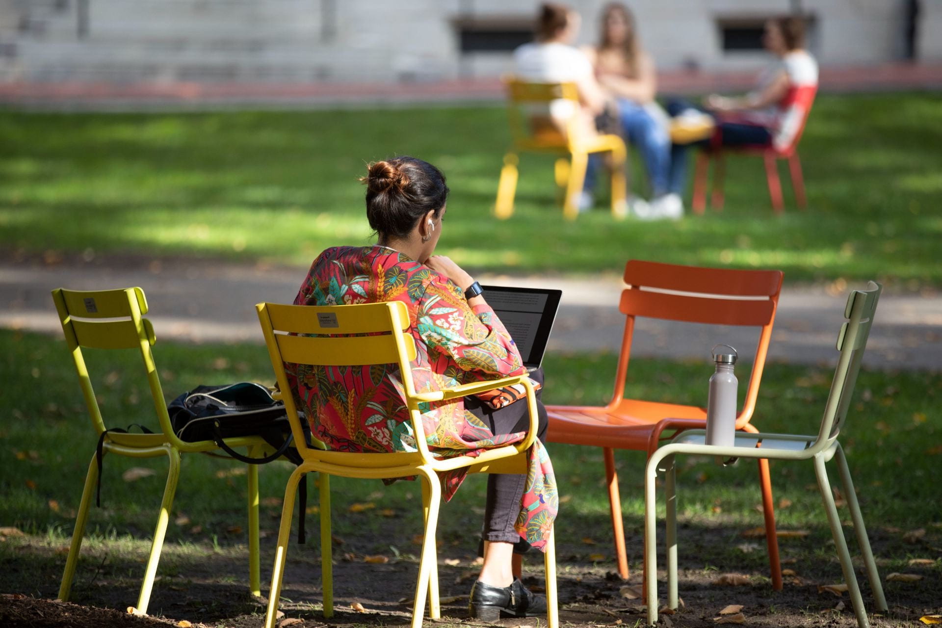 Image of woman studying in Harvard Yard as she sits on a lawn chair with her computer