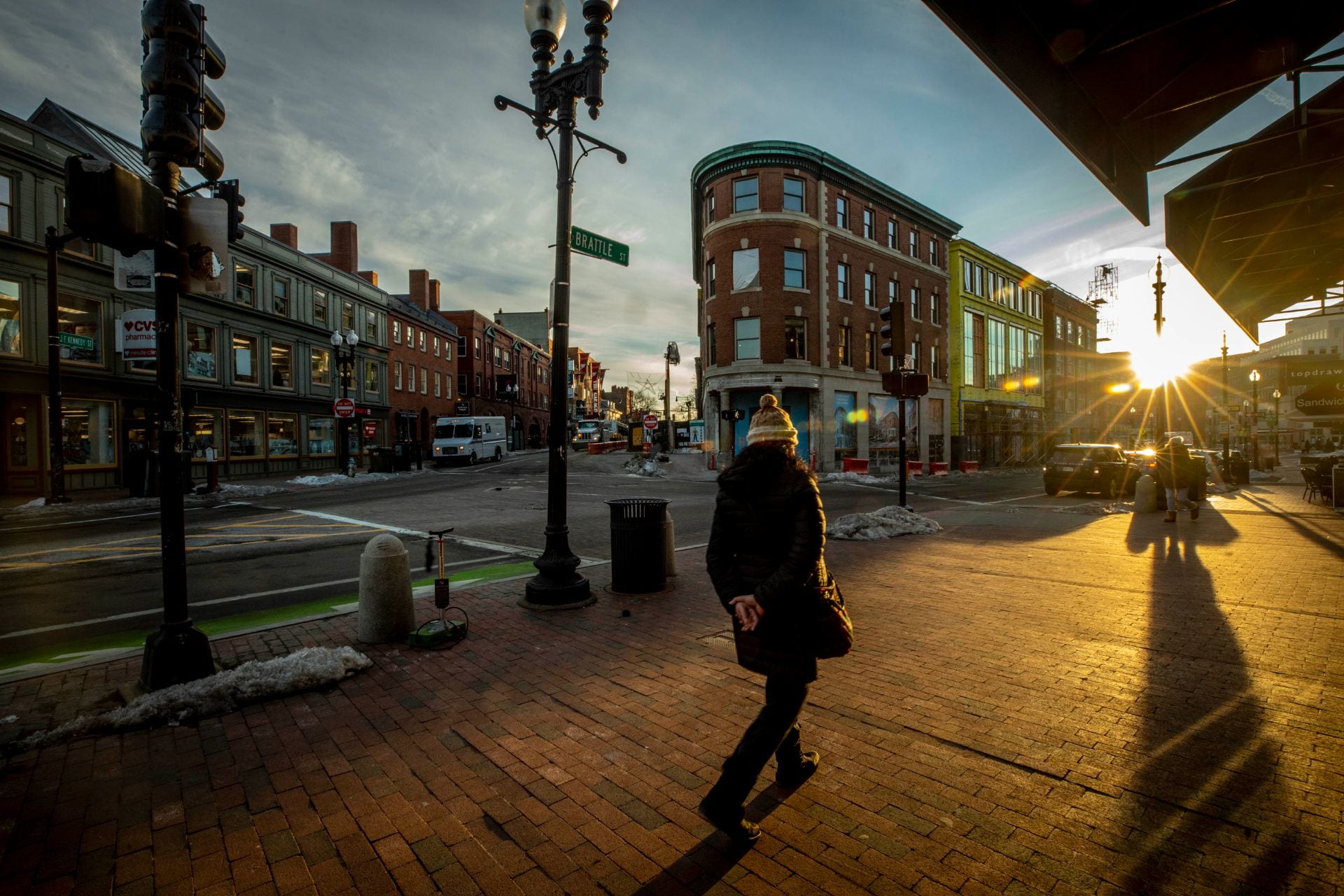 A woman walks through Harvard square during an early morning sunrise.