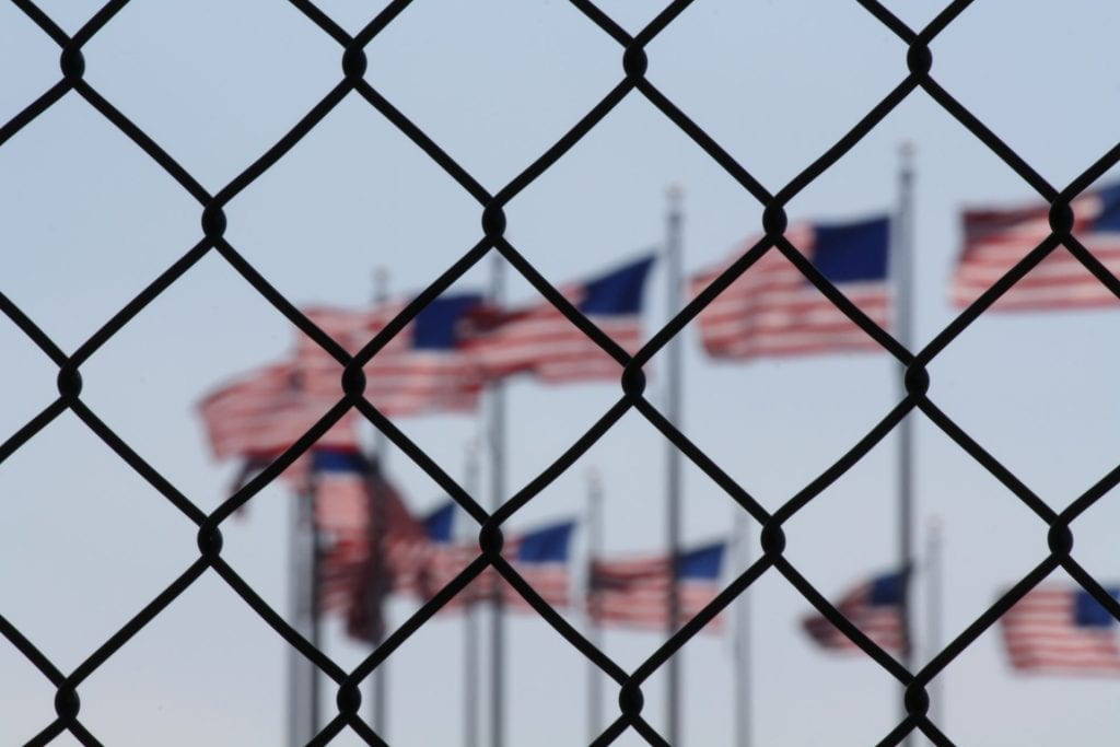 American flags seen behind a chain link fence.